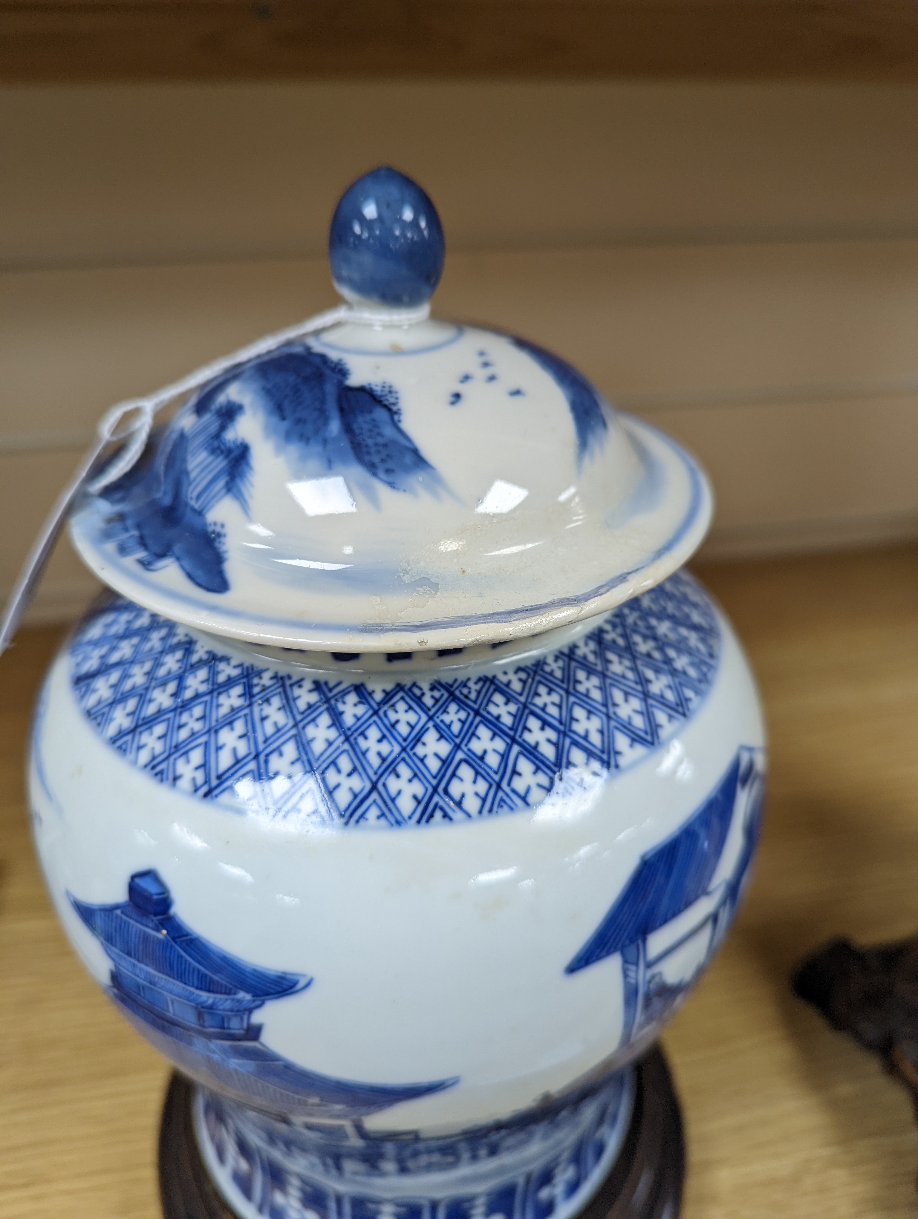 A late 19th / early 20th century Chinese blue and white landscape jar and cover, wood stand 30cm total height